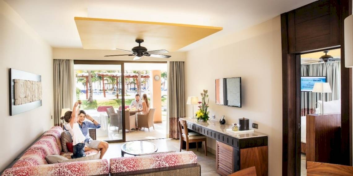 Suite-Wohnbereich im Barcelo Maya Beach mit offenem Balkon und Gartenblick.