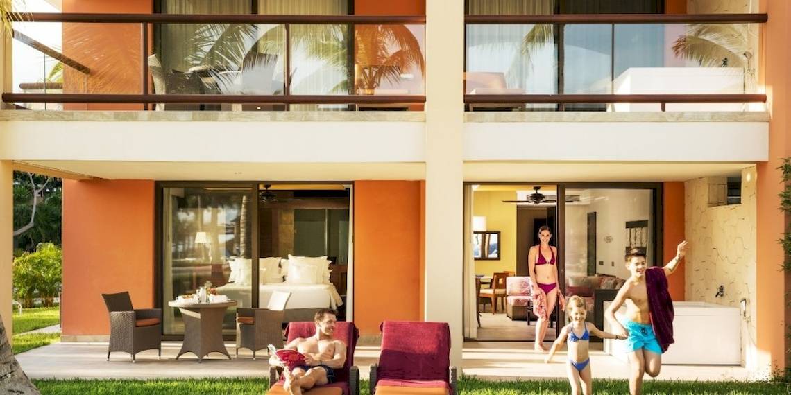 Familie genießt Urlaub im Barcelo Maya Beach Hotel mit Außenbereich, Liegestühlen und Pool.