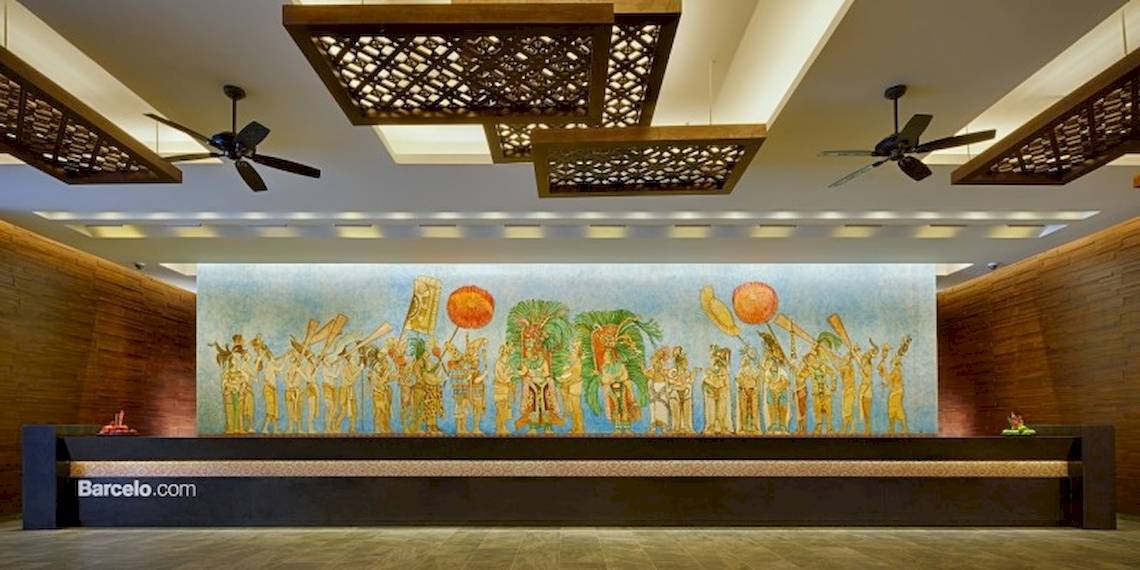 Lobby-Eingang des Barcelo Maya Beach Hotels mit großer Wandmalerei und Deckenventilatoren.