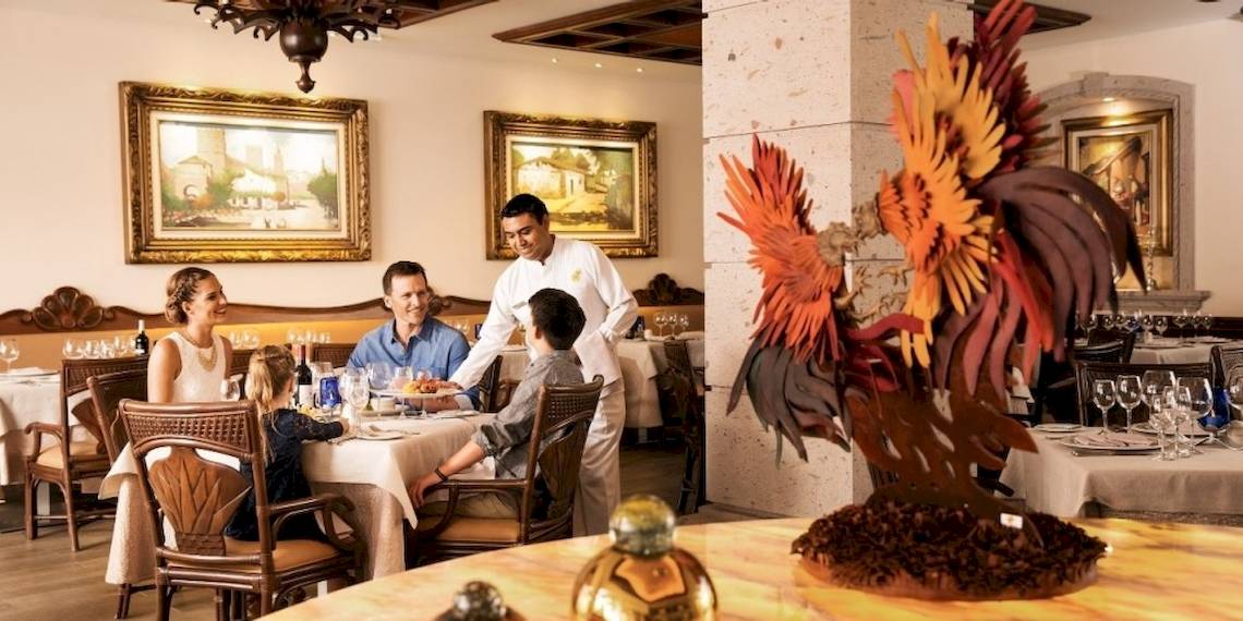 Familie in einem eleganten Restaurant des Barcelo Maya Beach Hotels, das Essen serviert wird