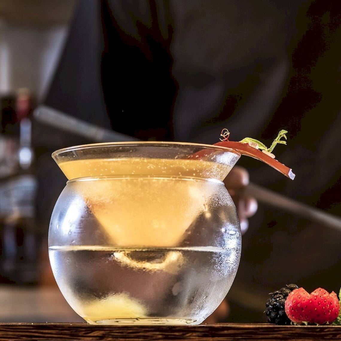 Ein Getränk in einem Glas mit Eis, dekoriert mit einer Fruchtscheibe und einigen Beeren.