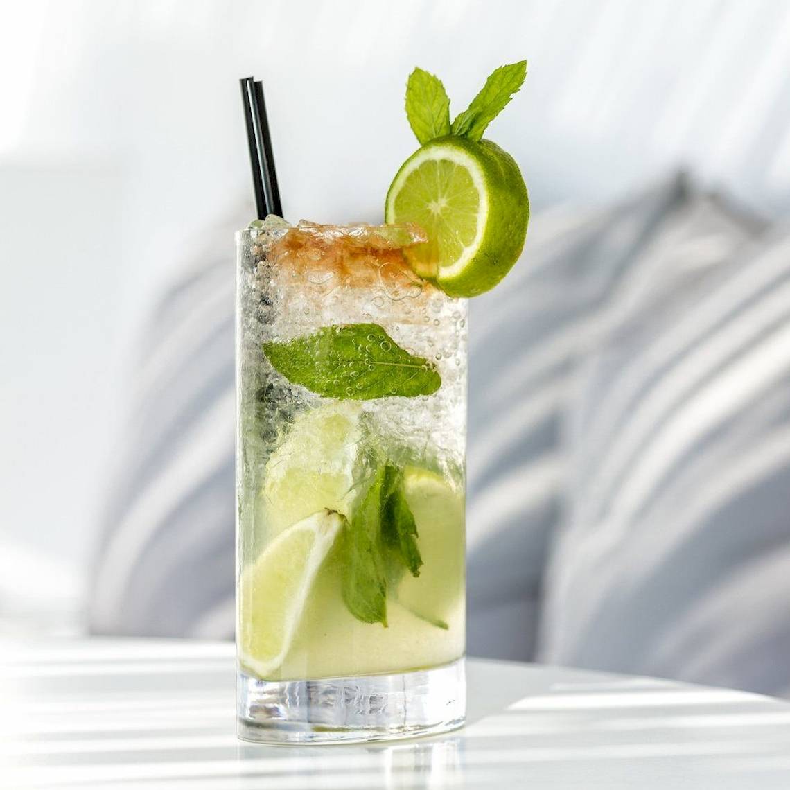 Ein Glas mit alkoholfreiem Cocktail, garniert mit Limetten und Minzblättern.
