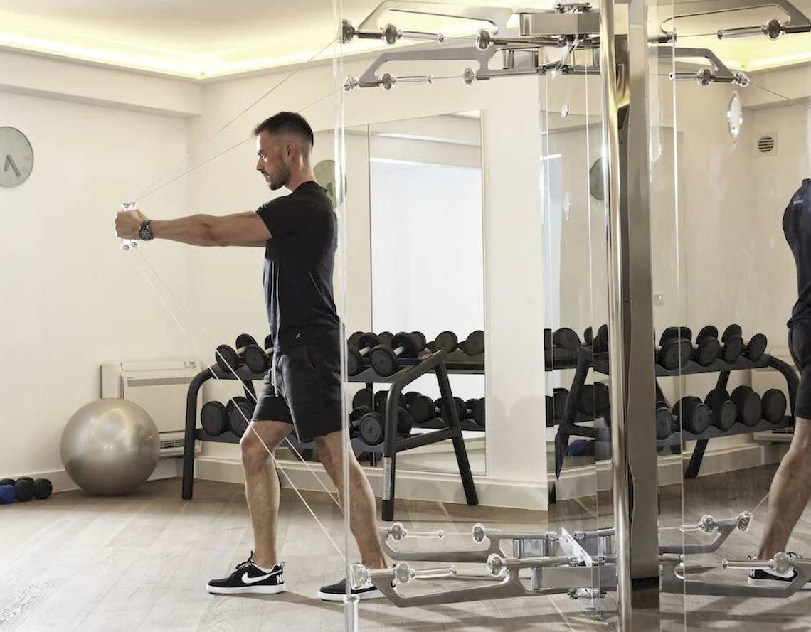 Mann trainiert in einem Fitnessstudio der Katikies Villas Mykonos mit einem Kabelzuggerät.