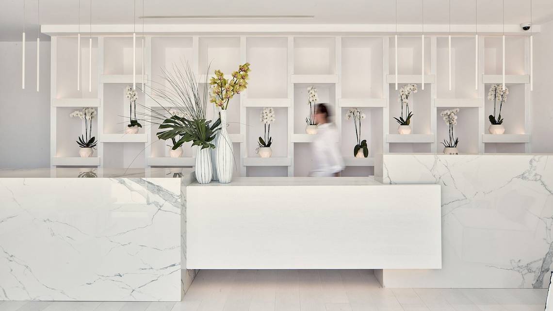 Empfangsbereich des Katikies Villas Mykonos Hotels mit weißen Marmor und Pflanzen in Vasen.
