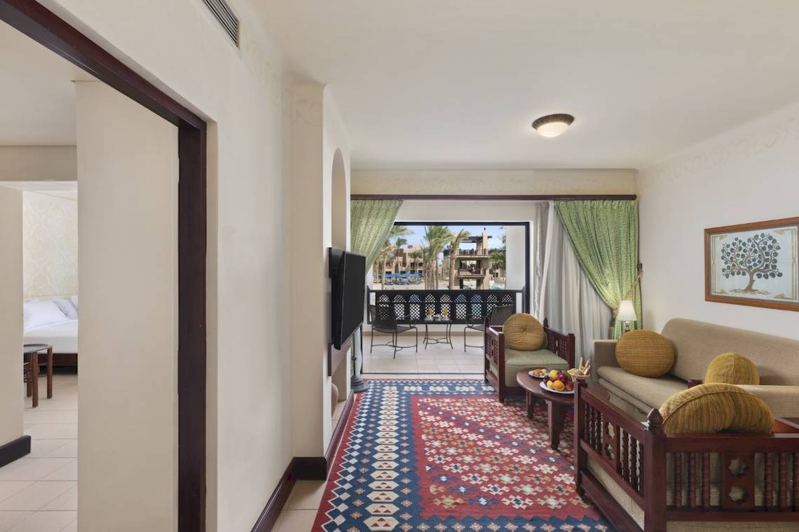 Wohnbereich des PickAlbatros Oasis Port Ghalib Hotels mit Sofa, Tisch, Fernseher und Balkon