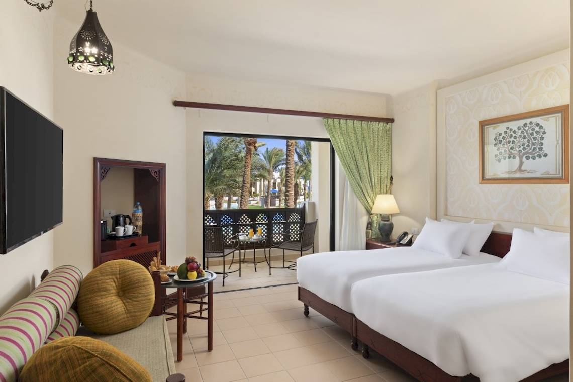 Doppelzimmer im PickAlbatros Oasis Port Ghalib Hotel mit Blick auf Palmen und Terrasse.