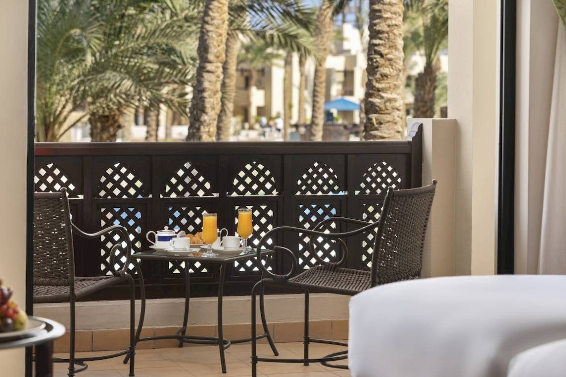 Frühstück auf dem Balkon des PickAlbatros Oasis Port Ghalib mit Blick auf Palmen und Gebäude.