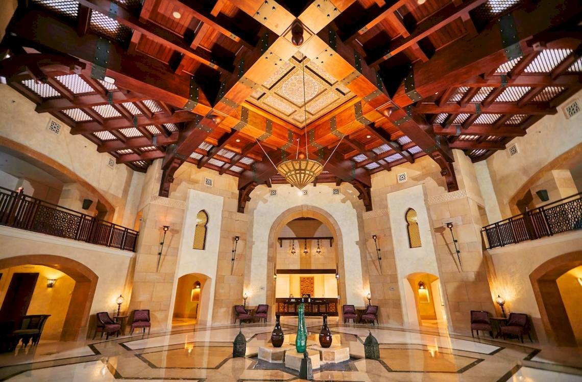 Innenansicht der Lobby des Pick Albatros Oasis Port Ghalib Hotels mit einer hohen Holzdecke und einem zentralen Brunnen.