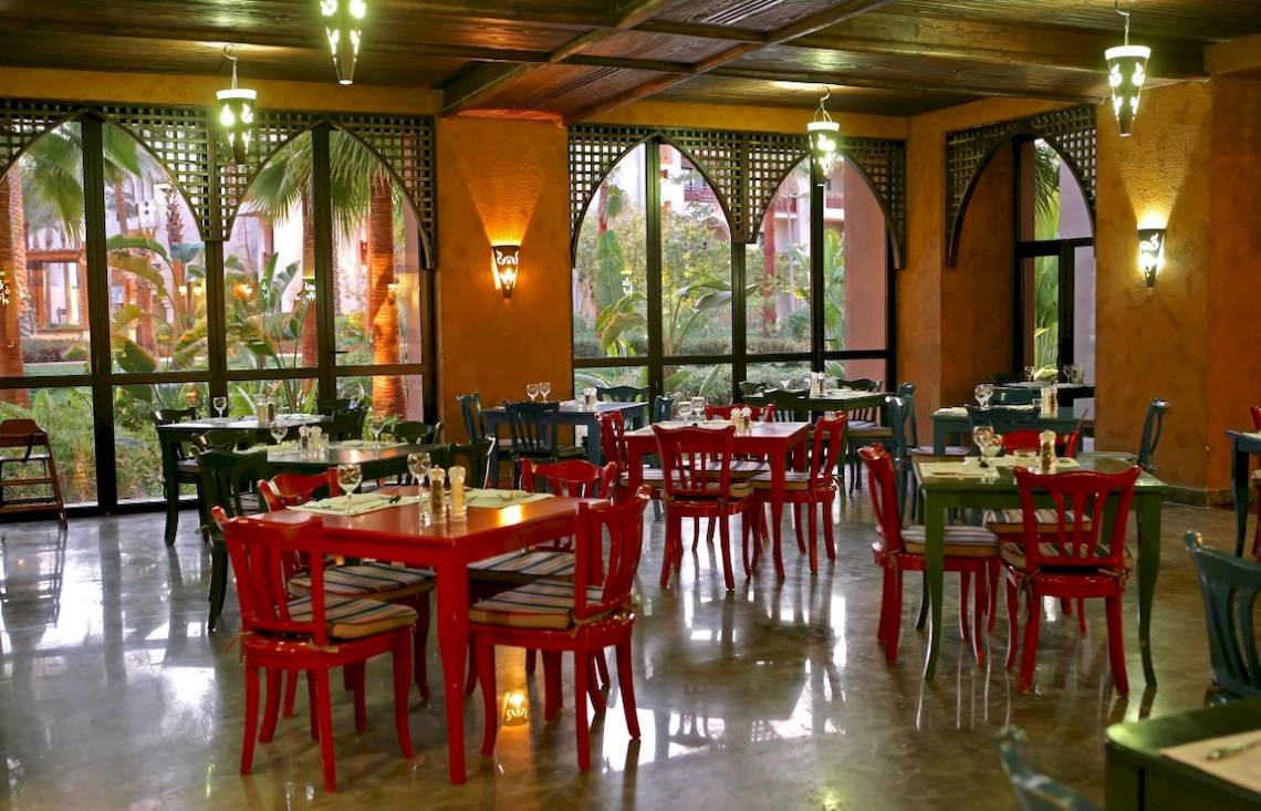 Innenansicht des Restaurants im Pick Albatros Oasis Port Ghalib Hotel mit roten Tischen und Stühlen.