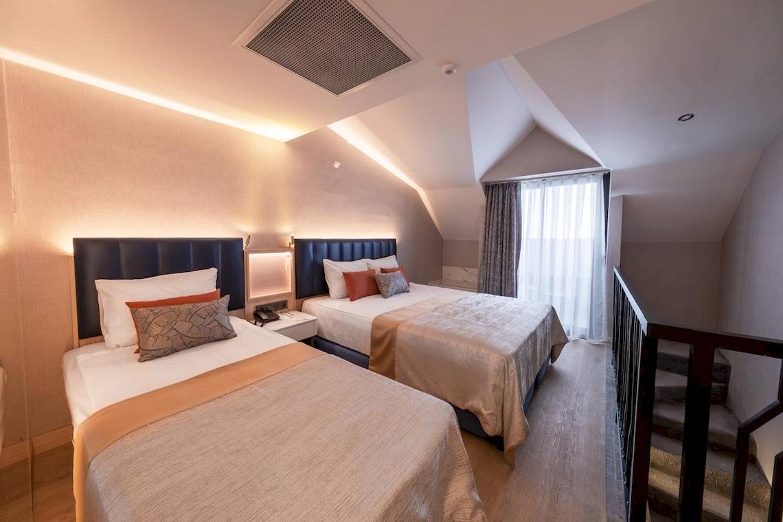 Doppelzimmer im Lago Hotel mit zwei Betten, Nachttischen und einer Treppe.