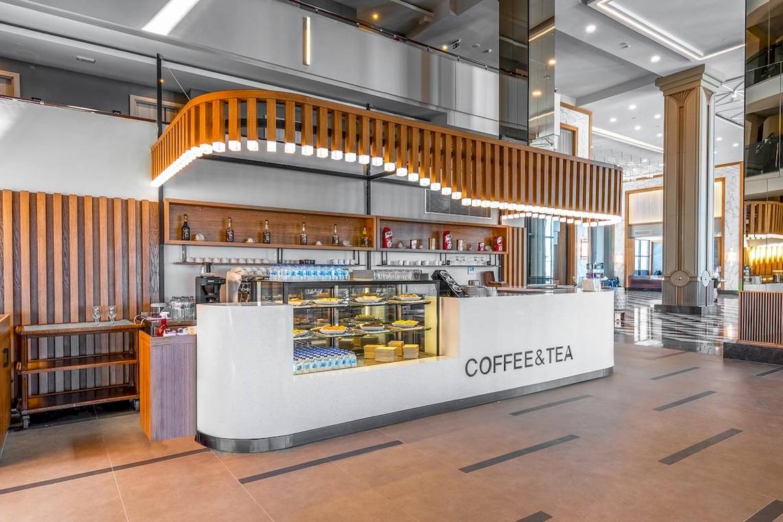 Innenansicht des Kaffee- und Tee-Schalters im Lago Hotel mit moderner Einrichtung und Holzelementen.