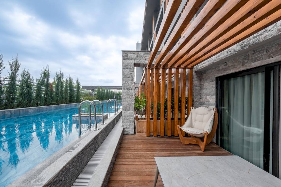 Außenbereich des Lago Hotels mit einem Pool und einer Holzterrasse.