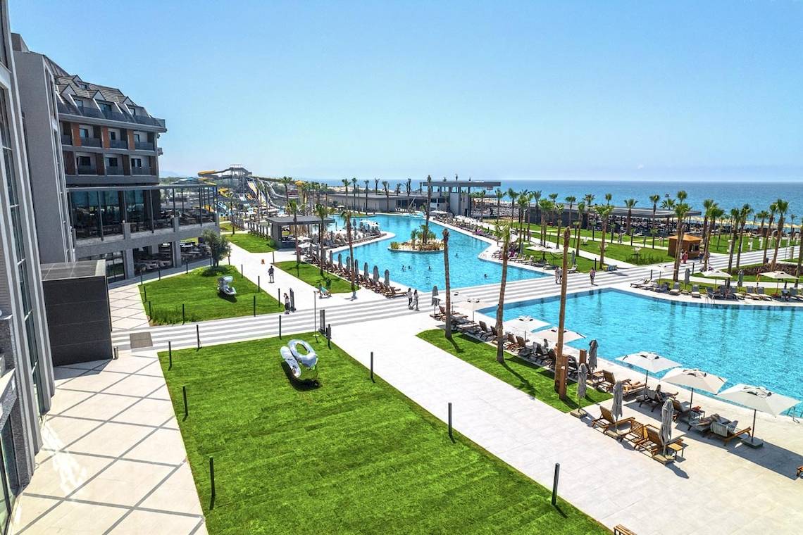 Luftaufnahme des Lago Hotels mit großen Swimmingpools, Palmen und Sonnenschirmen am Meer