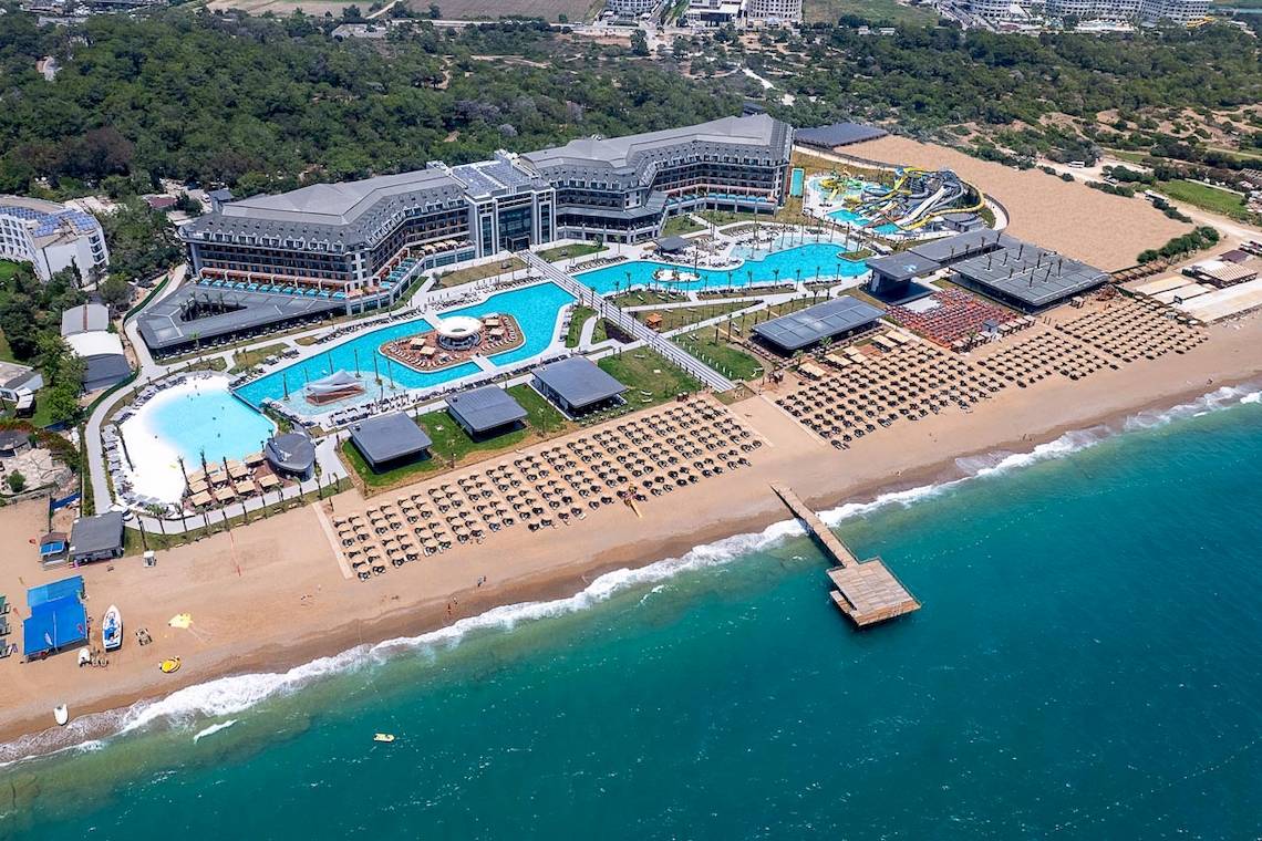 Luftaufnahme des Lago Hotels mit großem Swimmingpool, Wasserrutschen und Sonnenliegen am Strand