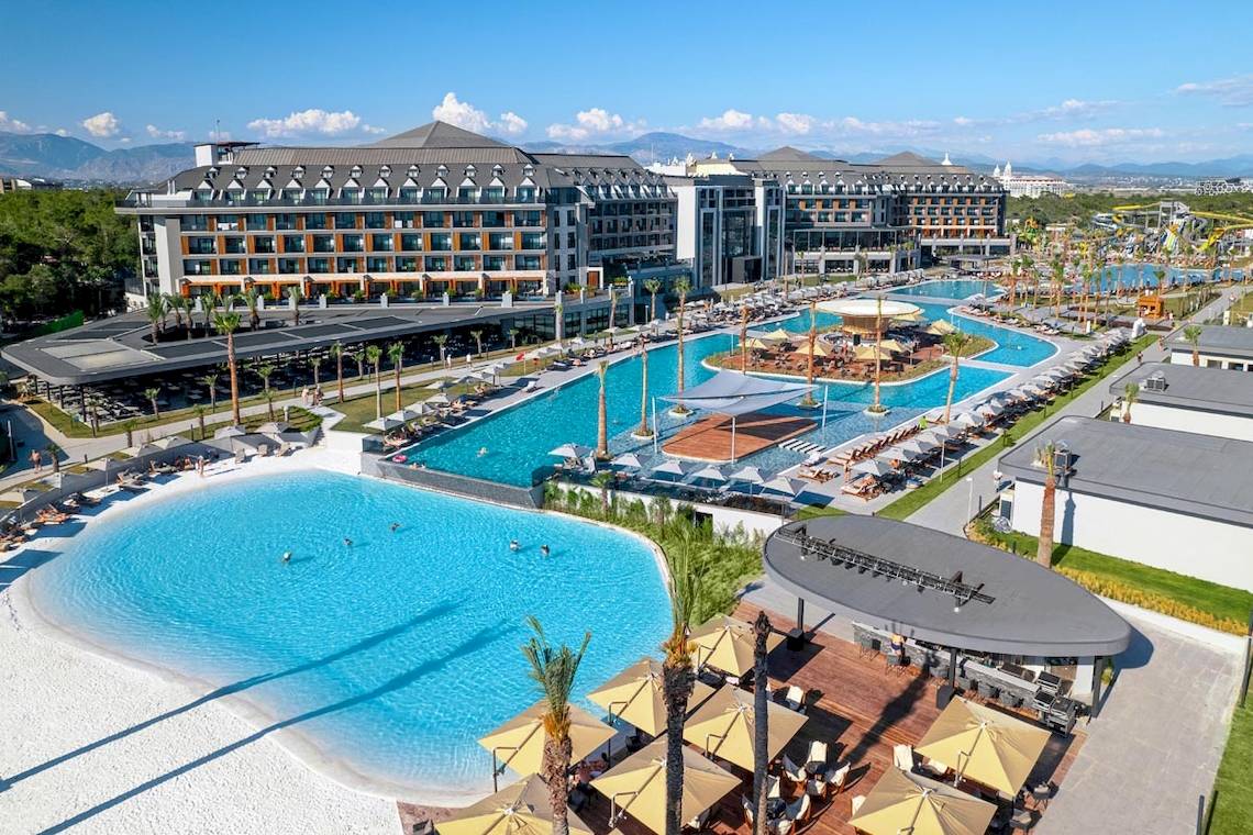 Oberflächenansicht des Lago Hotels mit Pools, Sonnenliegen, und umgebender Landschaft.