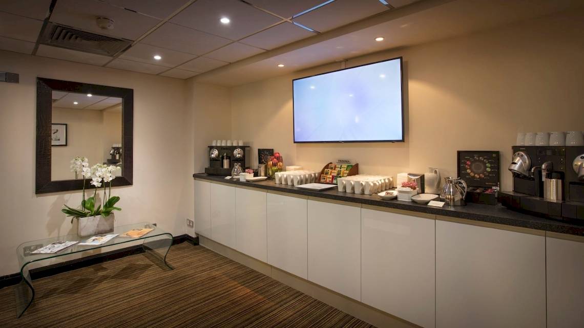 Frühstücksraum im Tower Hotel, London mit Fernseher, Kaffeemaschine und Frühstücksauswahl.