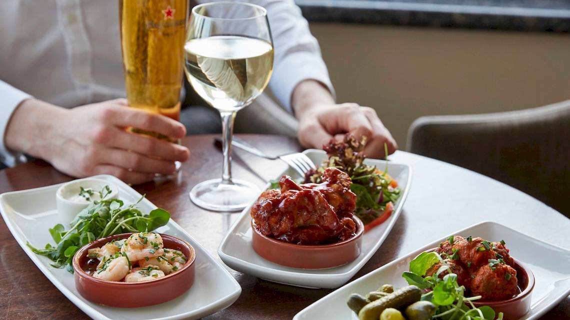 Ein Tisch im Tower Hotel, London, mit verschiedenen Gerichten und Getränken wie Wein und Bier.