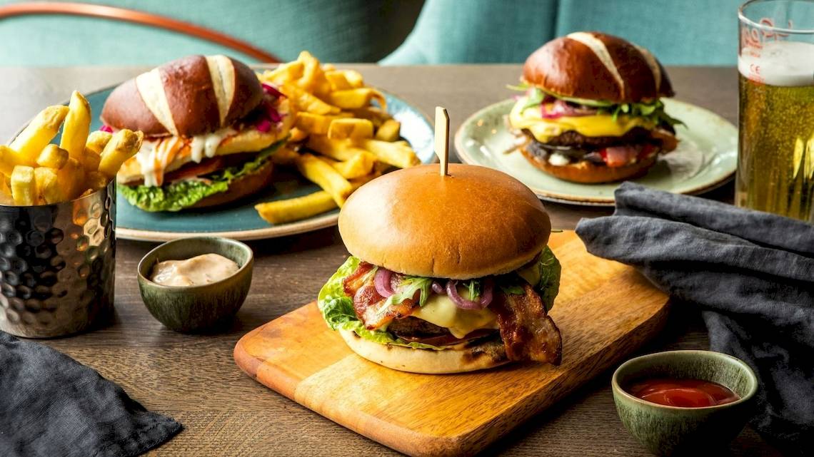 Zwei Burger mit Pommes und Beilagen auf einem Tisch im Tower Hotel, London.