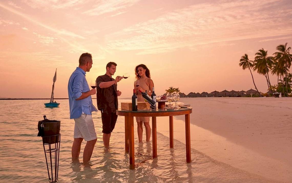 Drei Personen genießen Wein am Tisch auf dem Meer während des Sonnenuntergangs am Constance Ephelia Mahe Seychelles