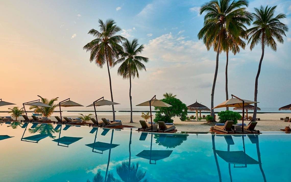 Außenpool des Constance Ephelia Mahe Seychelles mit Loungeliegen und Sonnenschirmen.