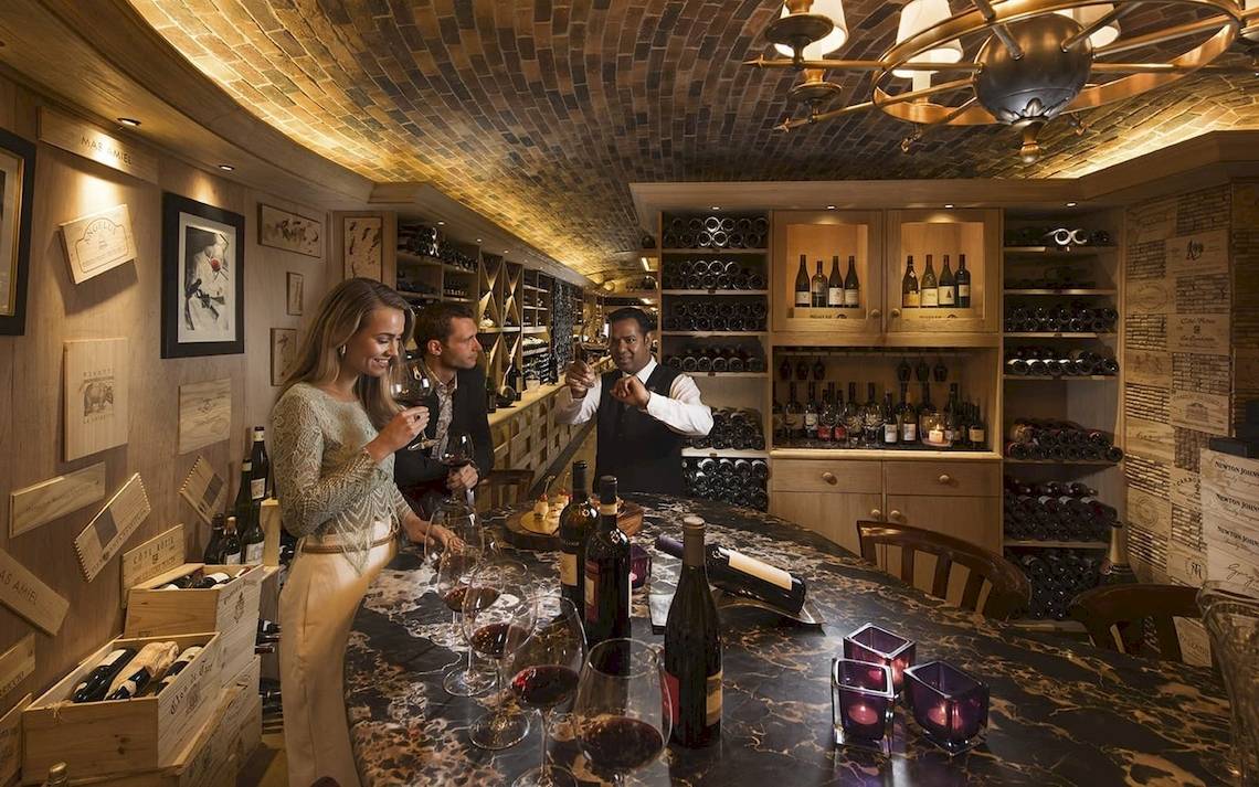 Ein Weinkeller im Constance Ephelia Mahe Seychelles mit Gästen, die Weinkelche halten.