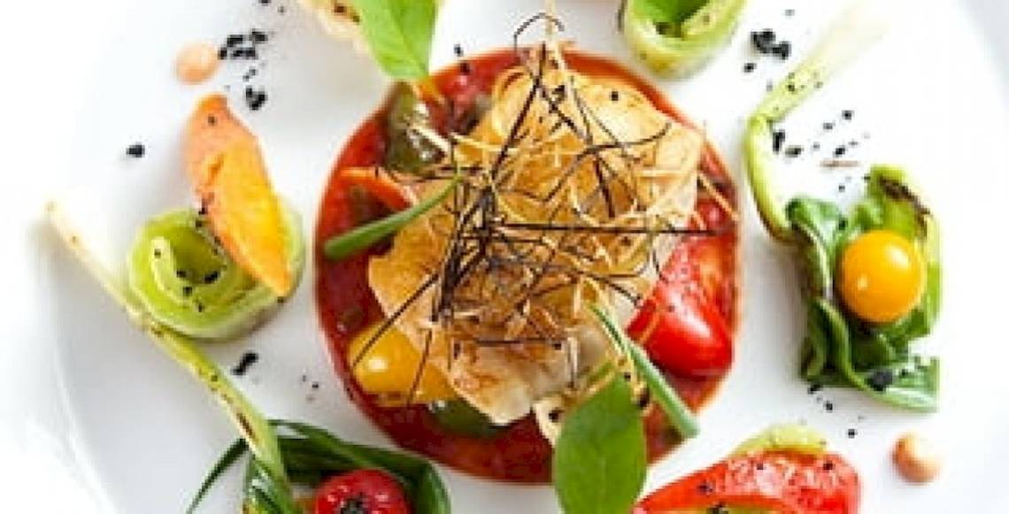 Gemüseplatte mit verschiedenen Tomaten und Blattgemüse auf einem weißen Teller