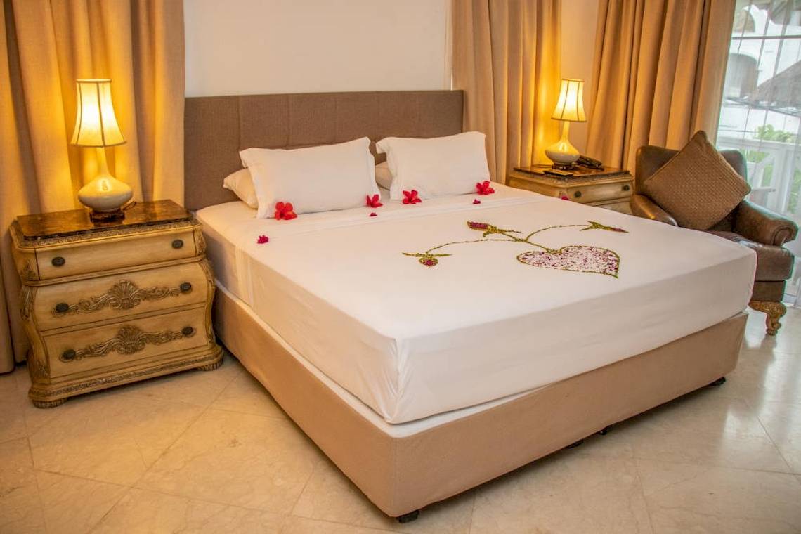Doppelbett im Zimmer des Dorf des Fischer Hotels mit Herz aus Blumen auf der Bettdecke.