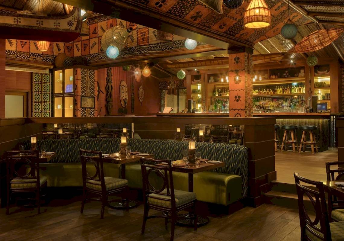 Innenbereich des STORY Seychelles Hotels mit Esstischen, Stühlen und Bar.