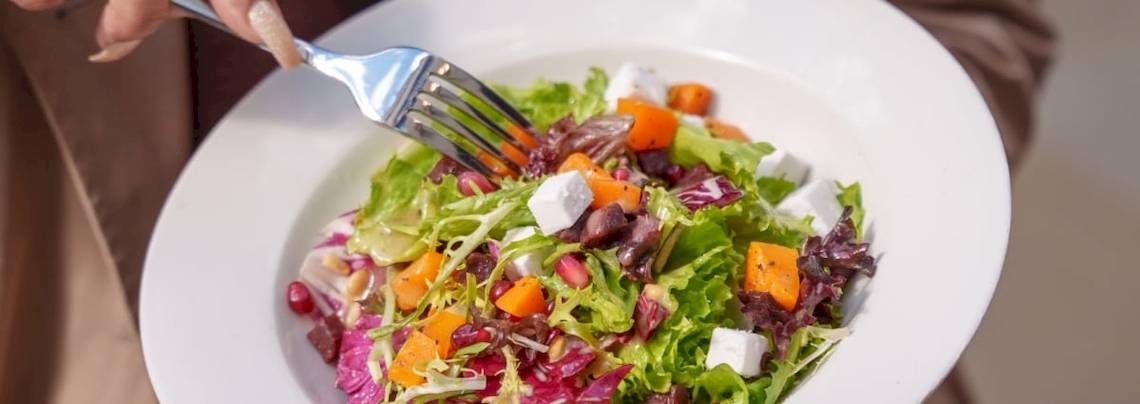 Ein Teller mit buntem Gemüsesalat, auf dem ein Löffel liegt.