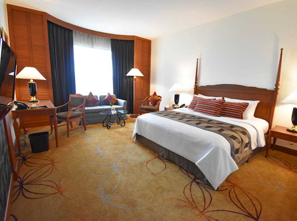 Hotelzimmer im Century Park Hotel mit Bett, Sofa, Schreibtisch und Lampen.