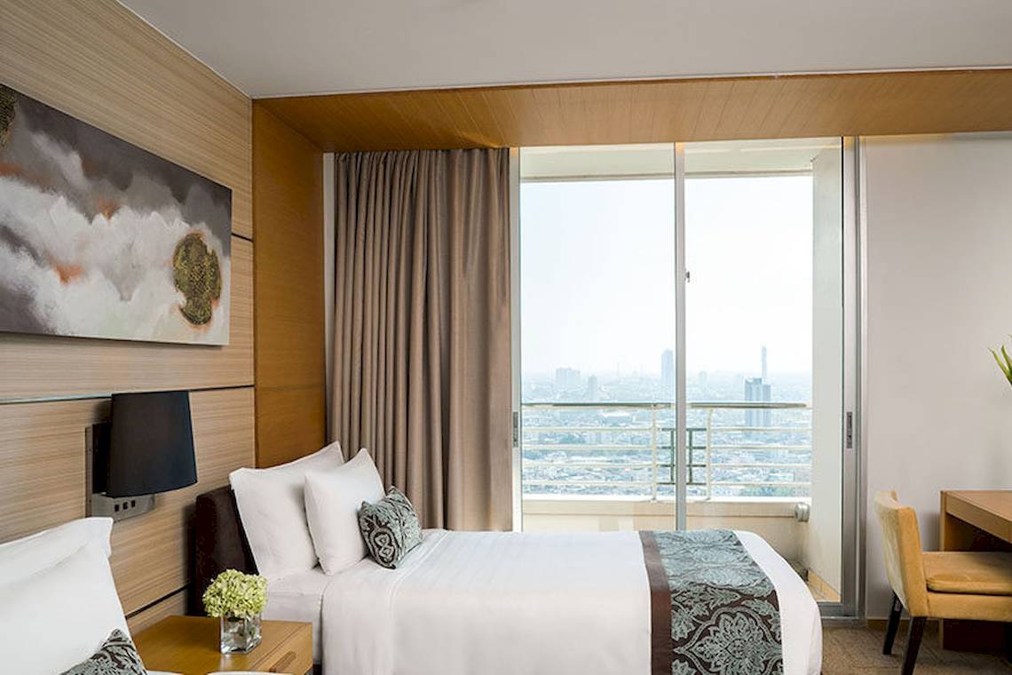 Hotelzimmer im JC Kevin Sathorn Bangkok mit zwei Betten, Ausblick und Schreibtisch.