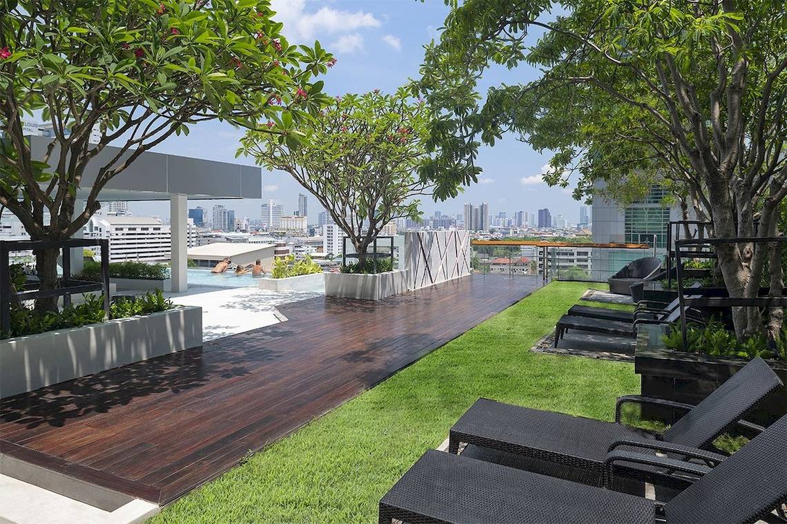 Terrasse des Mode Sathorn Hotels mit Swimmingpool und Liegestühlen.