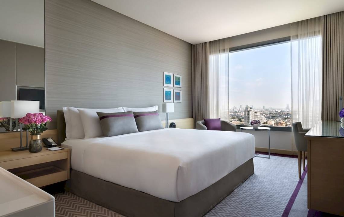 Hotelzimmer im AVANI+ Riverside Bangkok mit Stadtblick, modernem Design und bequemem Bett.
