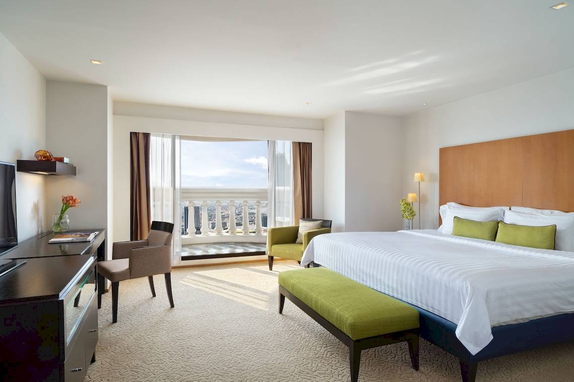 Innenansicht eines Hotelzimmers im Tower Club at Lebua mit Bett, Fenster und Stadtblick.