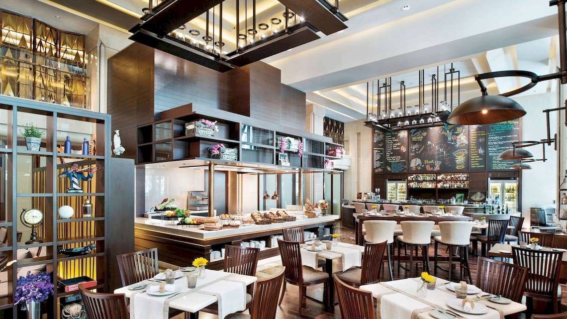Innenansicht des Restaurants im Siam Kempinski Hotel Bangkok mit Tisch, Stühlen und Buffet.