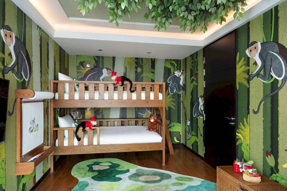Kinderzimmer im Siam Kempinski Hotel Bangkok mit grünen Wänden und Affen-Wandmalereien.