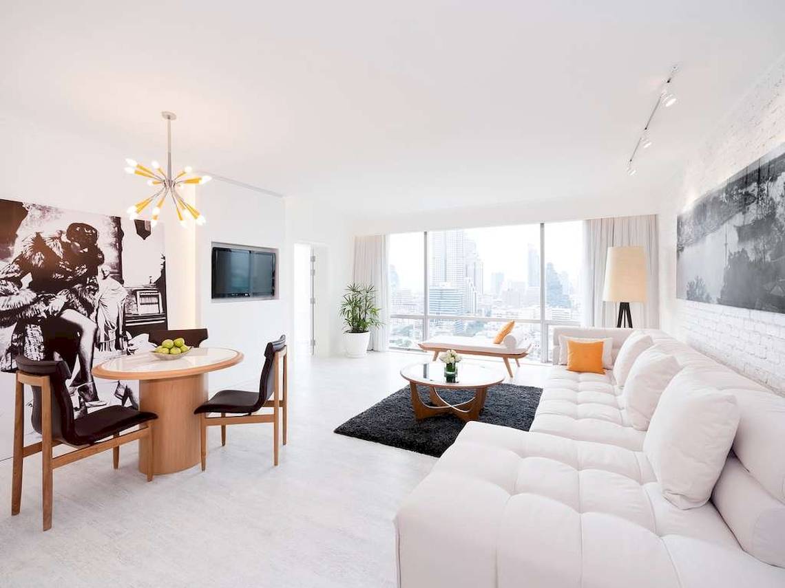 Modernes Wohnzimmer im Pullman Bangkok Hotel G mit weißem Sofa, Esstisch und Fernseher.