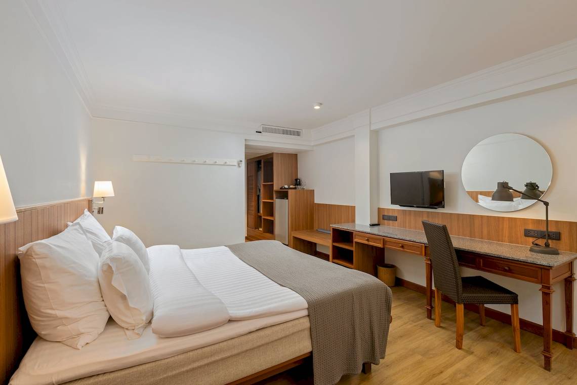 Innenansicht eines Hotelzimmers im Sunprime Kamala Beach mit Bett, Schreibtisch und Fernseher.
