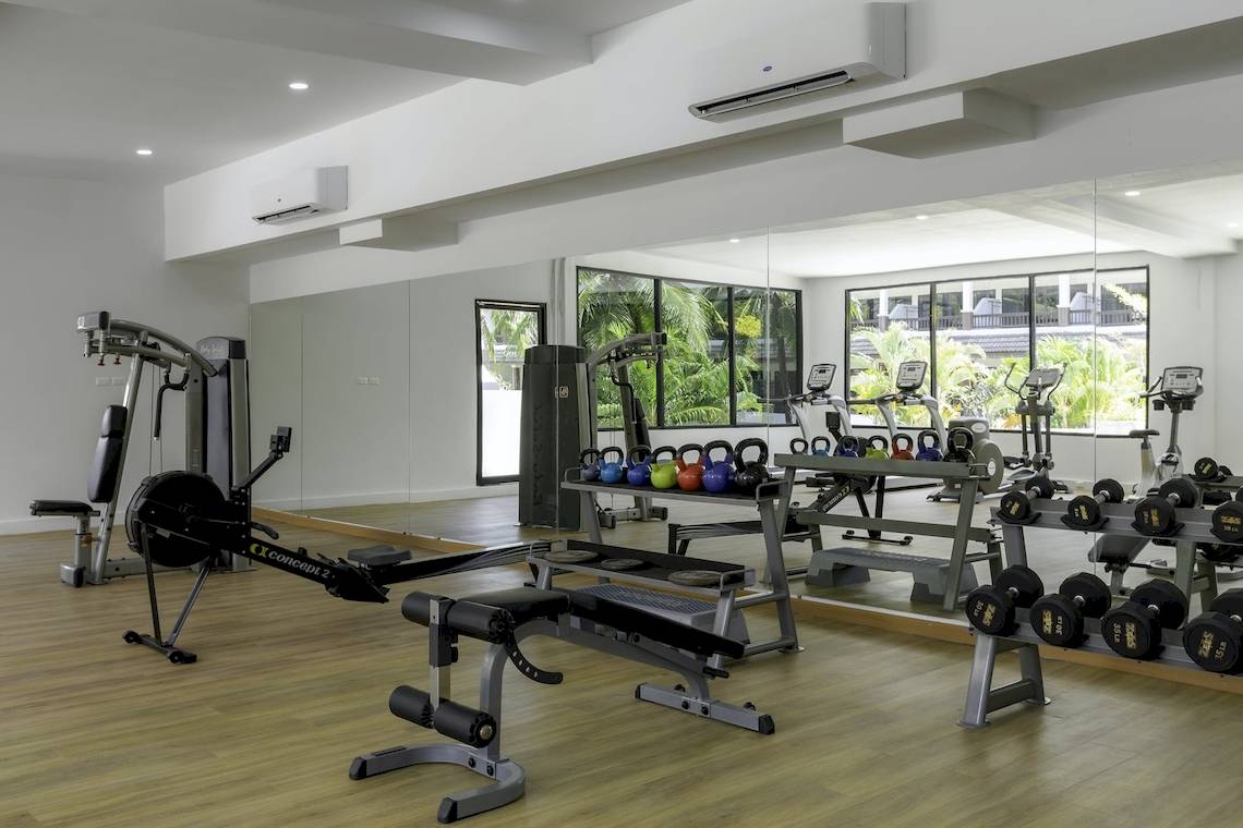 Fitnessraum im Sunprime Kamala Beach Hotel mit verschiedenen Trainingsgeräten und Spiegeln.
