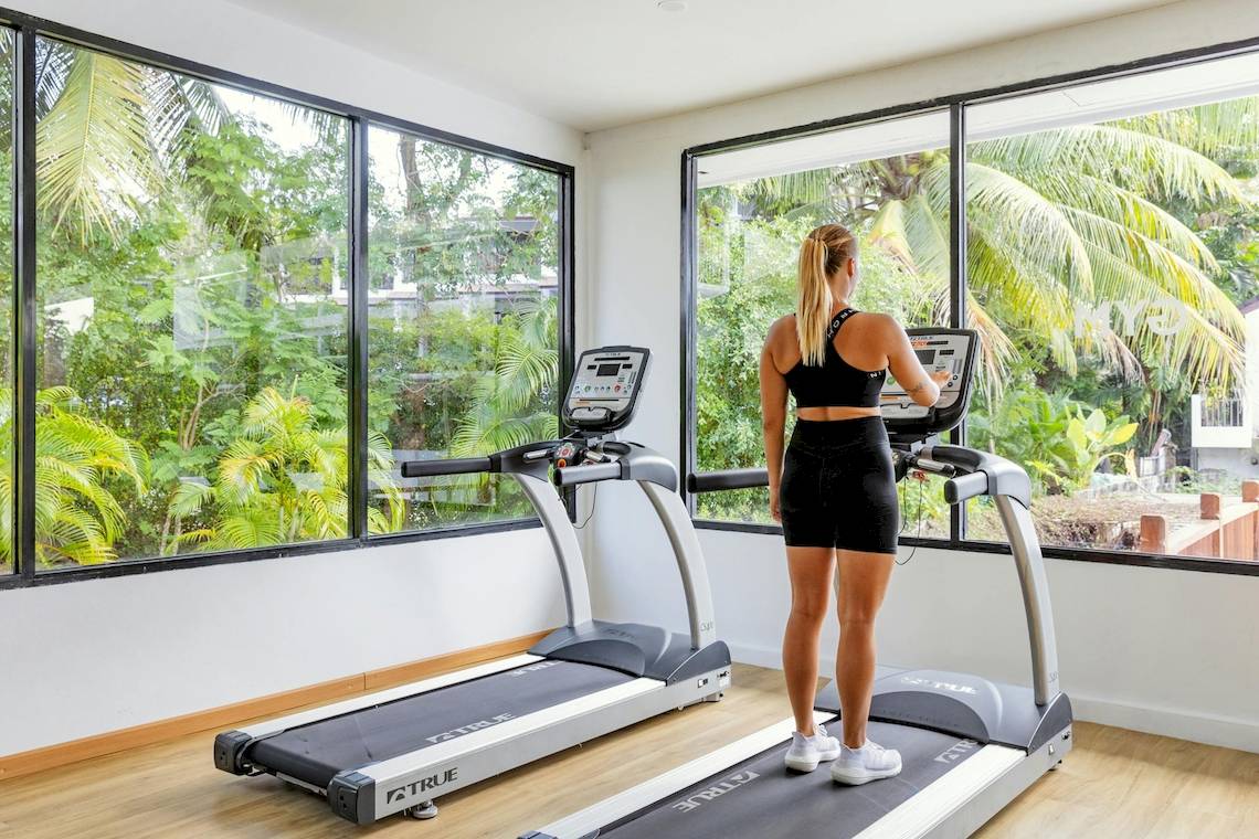 Frau trainiert auf einem Laufband im Fitnessraum des Sunprime Kamala Beach Hotels.
