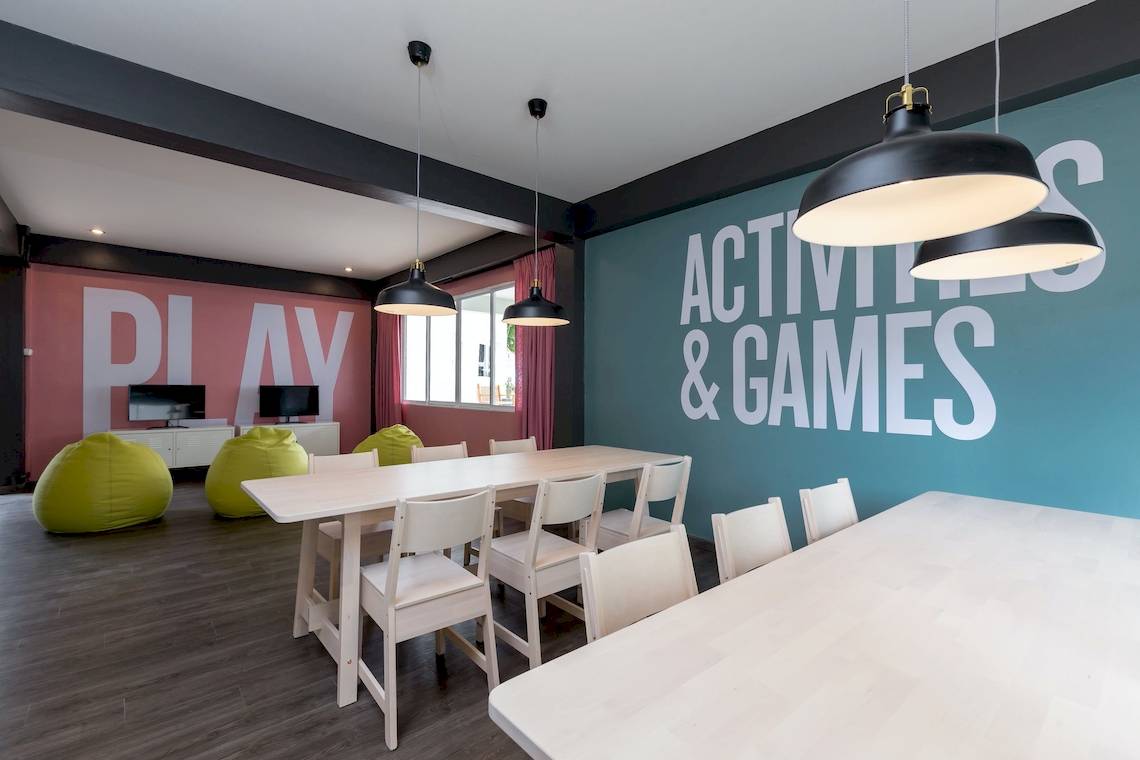 Spielzimmer im Sunwing Bangtao Beach Hotel mit Tischen, Stühlen, Hängelampen und bunten Sofas.