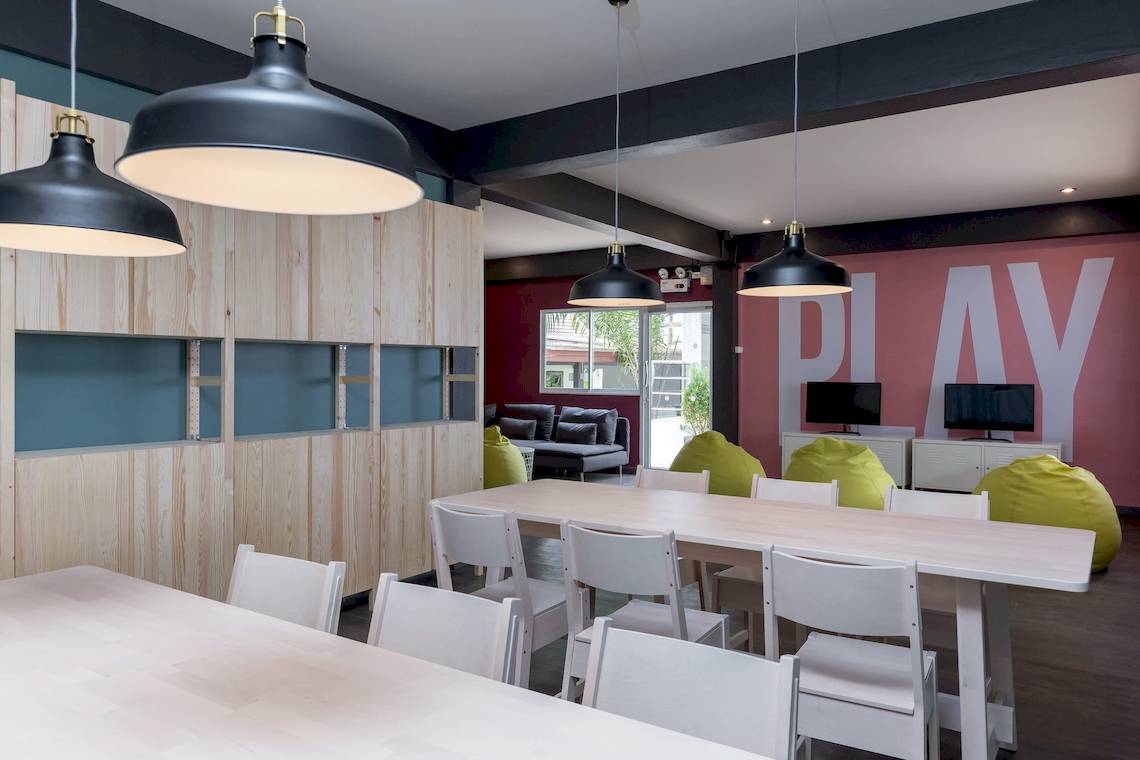Spielzimmer im Sunwing Bangtao Beach Hotel mit Tischen, Stühlen, gelben Beanbags und Monitoren.