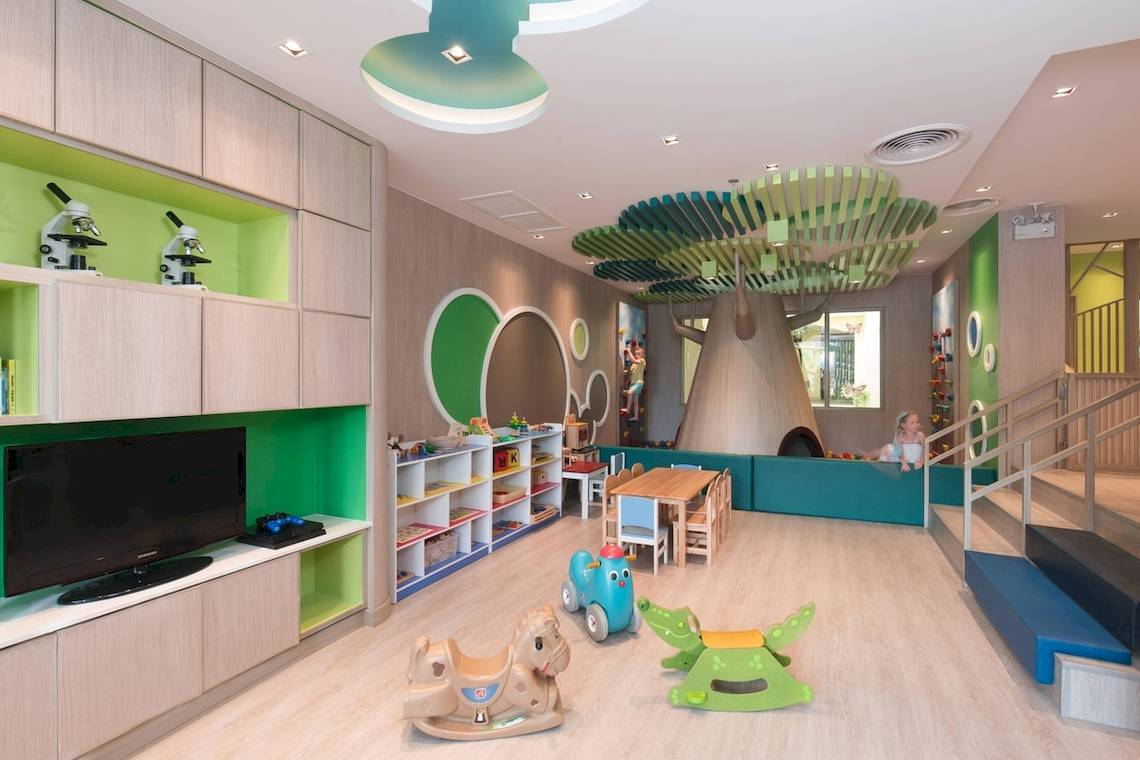 Kinderspielzimmer im Phuket Marriott Resort & Spa Merlin Beach mit Fernseher, Bücherregal, Spieltischen und Baum-Dekoration.
