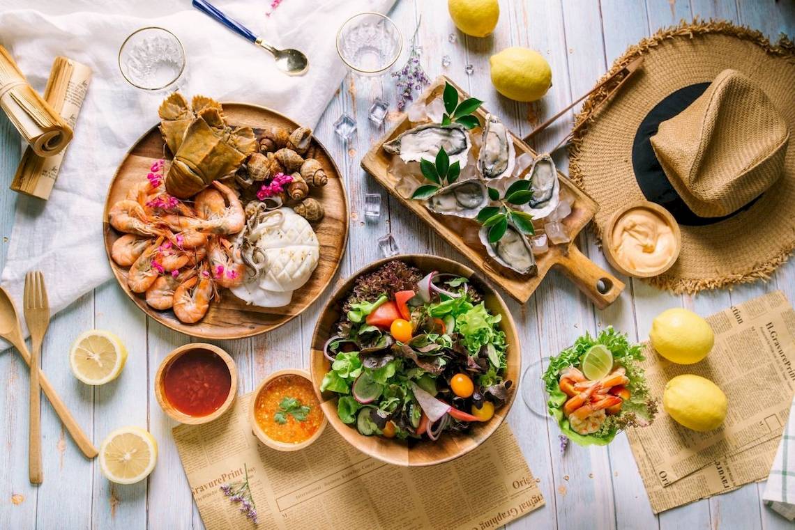 Ein Gericht auf einem Holztisch mit Meeresfrüchten, Salat und Austern.