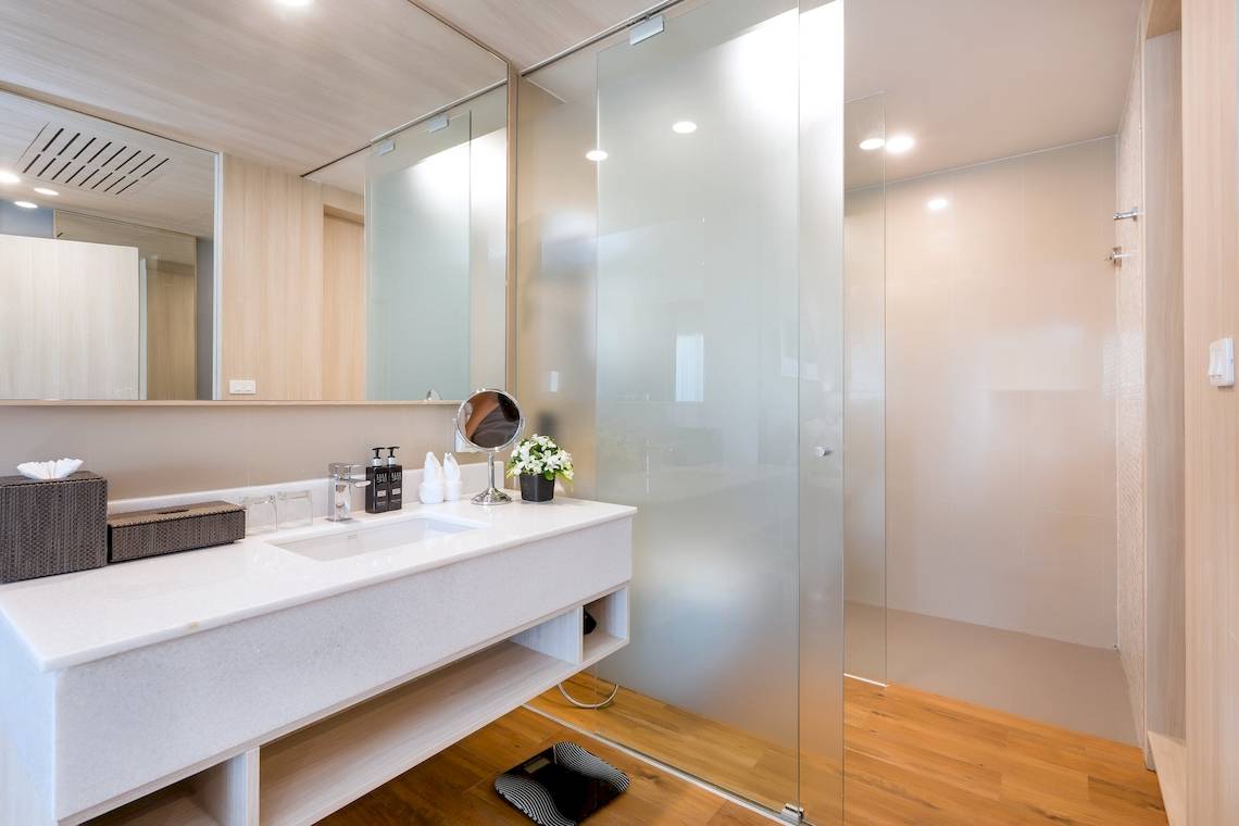 Ein modernes Badezimmer im X10 Khaolak Resort mit einem Waschbecken, Spiegel, und Glasdusche.