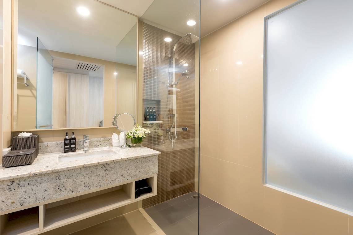 Badezimmer im X10 Khaolak Resort mit Marmor-Waschtisch und Glasdusche.