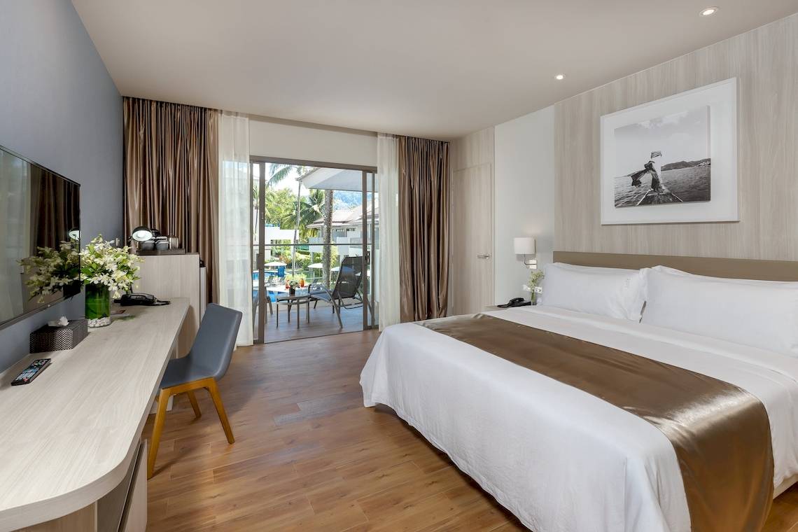Hotelzimmer im X10 Khaolak Resort mit einem großen Bett, Schreibtisch und Zugang zur Terrasse.