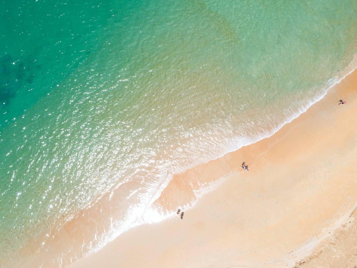 Oberflächenansicht eines Strandes mit Meer und Leuten, die auf dem Sand und im Wasser sind