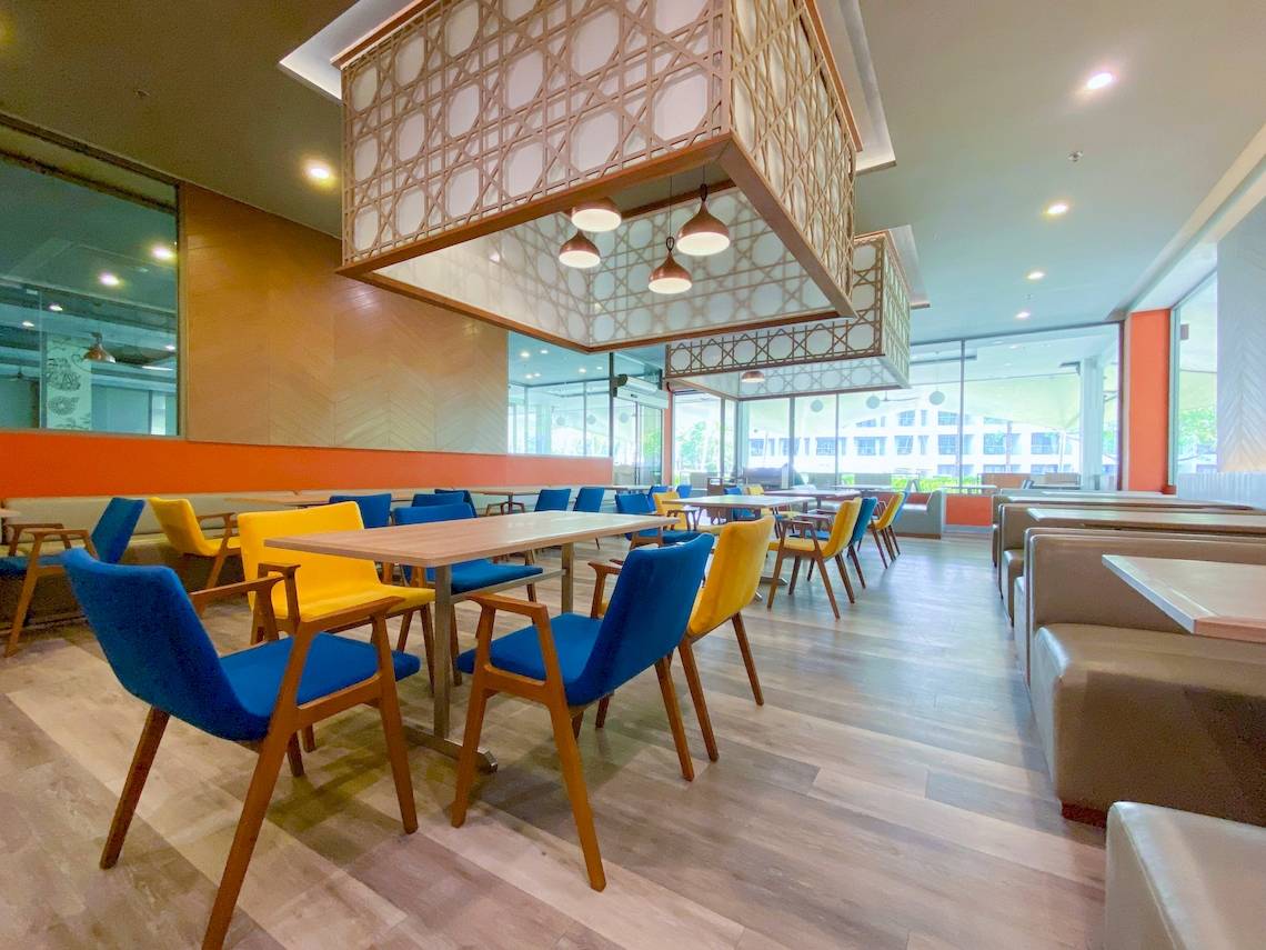 Innenbereich des X10 Khaolak Resorts mit blauen und gelben Stühlen und Tischen, modernes Design, Holzboden.