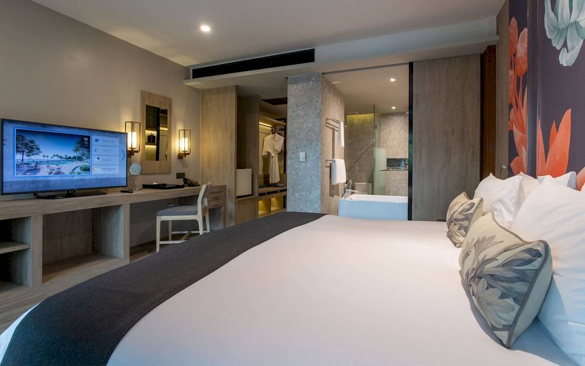 Innenansicht eines Hotelzimmers von La Flora Khao Lak mit Bett, Fernseher und Schreibtisch.